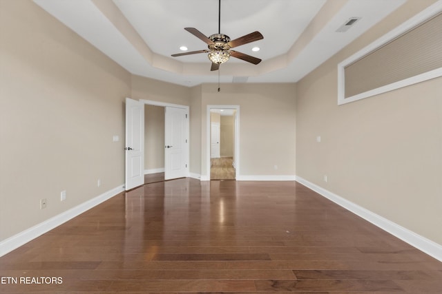 unfurnished room with dark hardwood / wood-style floors, ceiling fan, and a tray ceiling