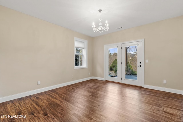 spare room with a chandelier, hardwood / wood-style flooring, and a wealth of natural light