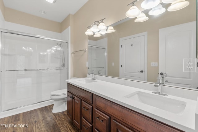 bathroom featuring hardwood / wood-style flooring, vanity, toilet, and a shower with door