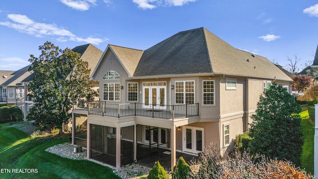 rear view of house featuring a lawn, a balcony, and french doors