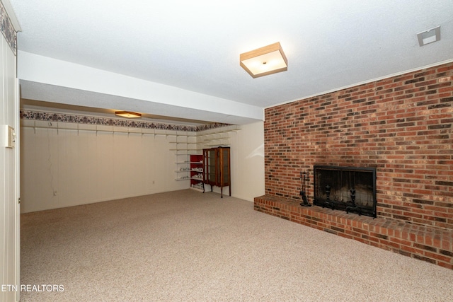 unfurnished living room featuring a textured ceiling, carpet floors, and a brick fireplace