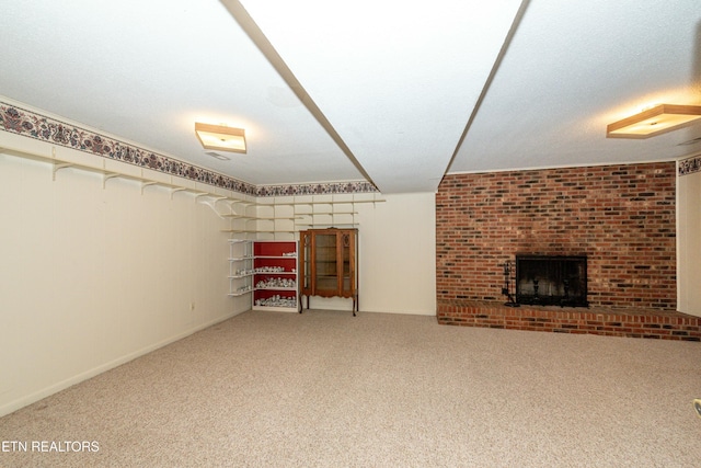 basement with carpet, a textured ceiling, a fireplace, and brick wall