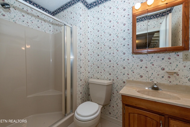 bathroom with a textured ceiling, vanity, toilet, and a shower with door