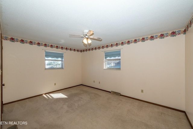 carpeted spare room featuring ceiling fan and a wealth of natural light