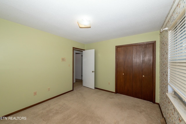 unfurnished bedroom featuring a textured ceiling, light colored carpet, and a closet