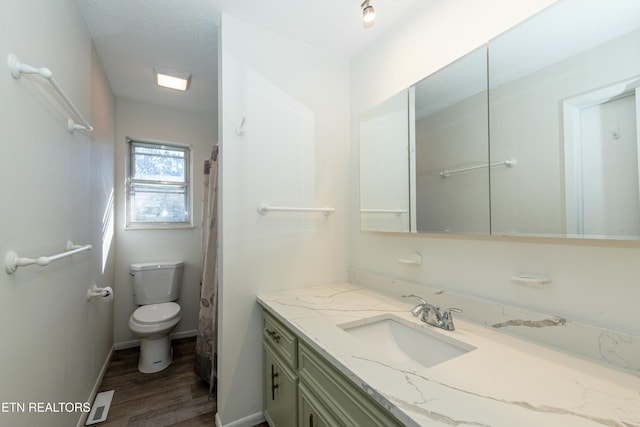 bathroom featuring hardwood / wood-style floors, vanity, toilet, and a textured ceiling