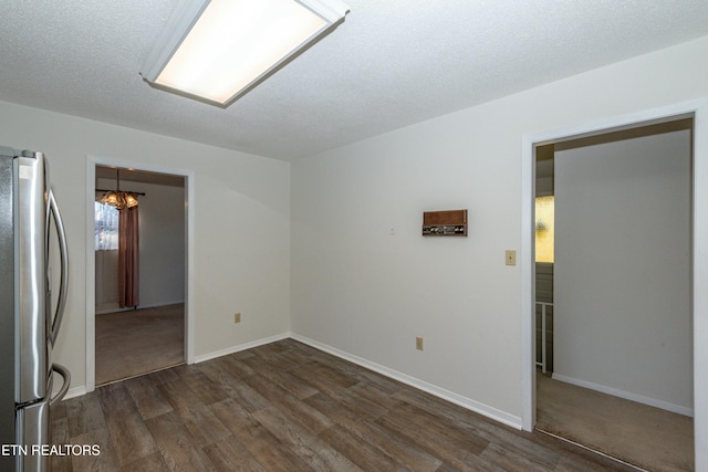 spare room with a textured ceiling, dark hardwood / wood-style flooring, and a notable chandelier