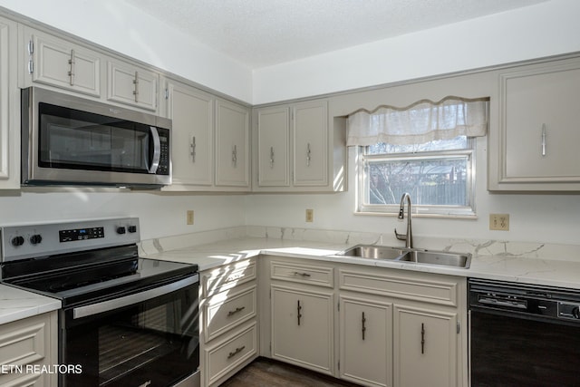 kitchen with appliances with stainless steel finishes, dark hardwood / wood-style floors, light stone counters, and sink