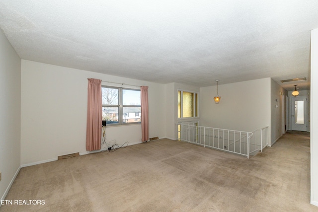 unfurnished room featuring light carpet and a textured ceiling