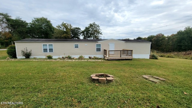 rear view of property featuring a yard, a fire pit, and a wooden deck