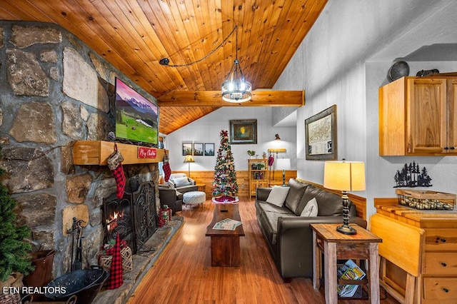 living room with hardwood / wood-style flooring, lofted ceiling with beams, a stone fireplace, and wooden ceiling