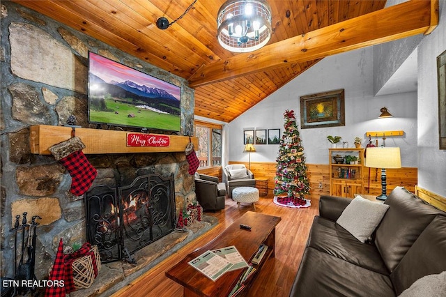 living room with hardwood / wood-style flooring, lofted ceiling with beams, a stone fireplace, and wooden ceiling