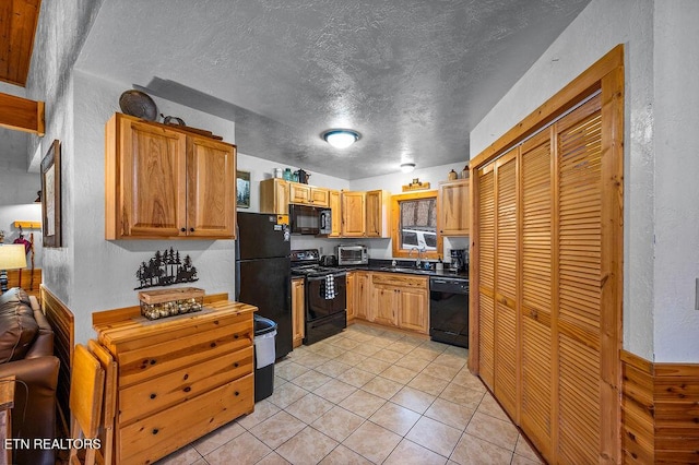 kitchen featuring black appliances, light tile patterned floors, sink, and a textured ceiling