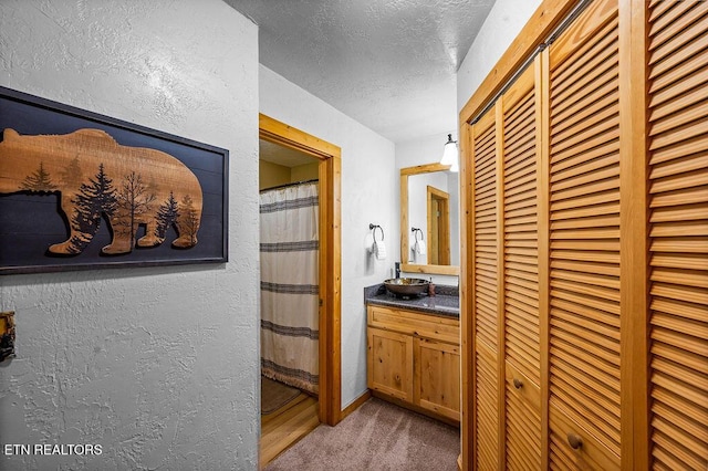 hallway featuring light colored carpet and a textured ceiling