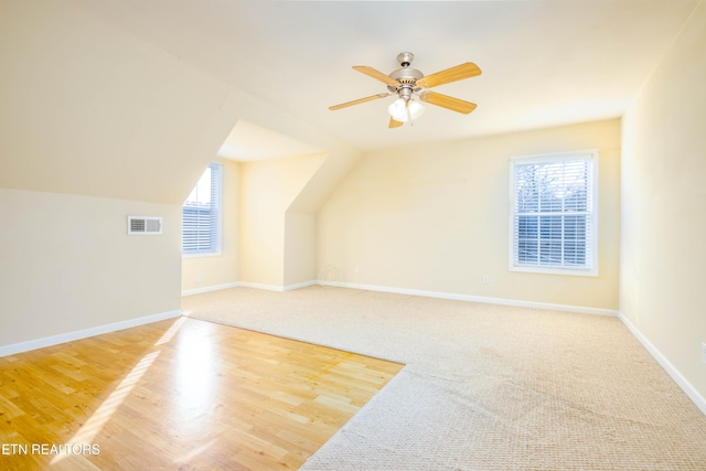 additional living space with baseboards, lofted ceiling, visible vents, and a healthy amount of sunlight