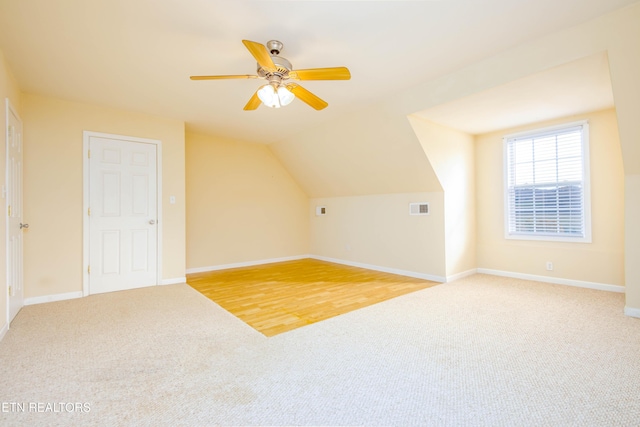 additional living space with lofted ceiling, visible vents, a ceiling fan, light carpet, and baseboards