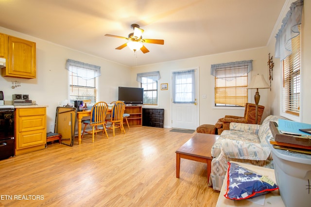 living room with a ceiling fan, ornamental molding, and light wood finished floors