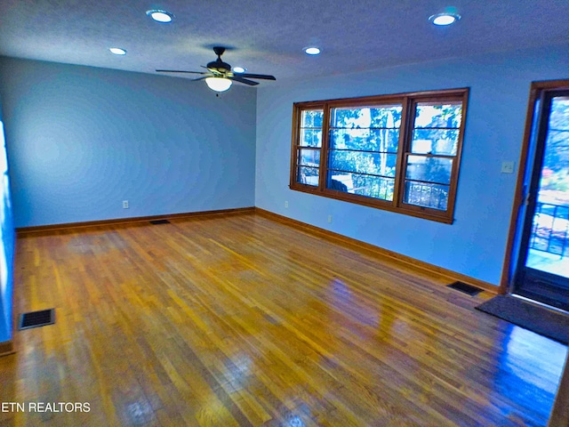 empty room with hardwood / wood-style flooring, ceiling fan, and a textured ceiling