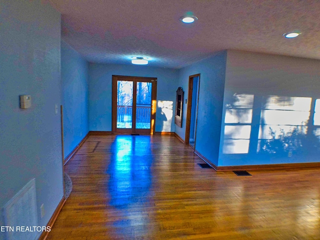 unfurnished room with dark hardwood / wood-style flooring and a textured ceiling