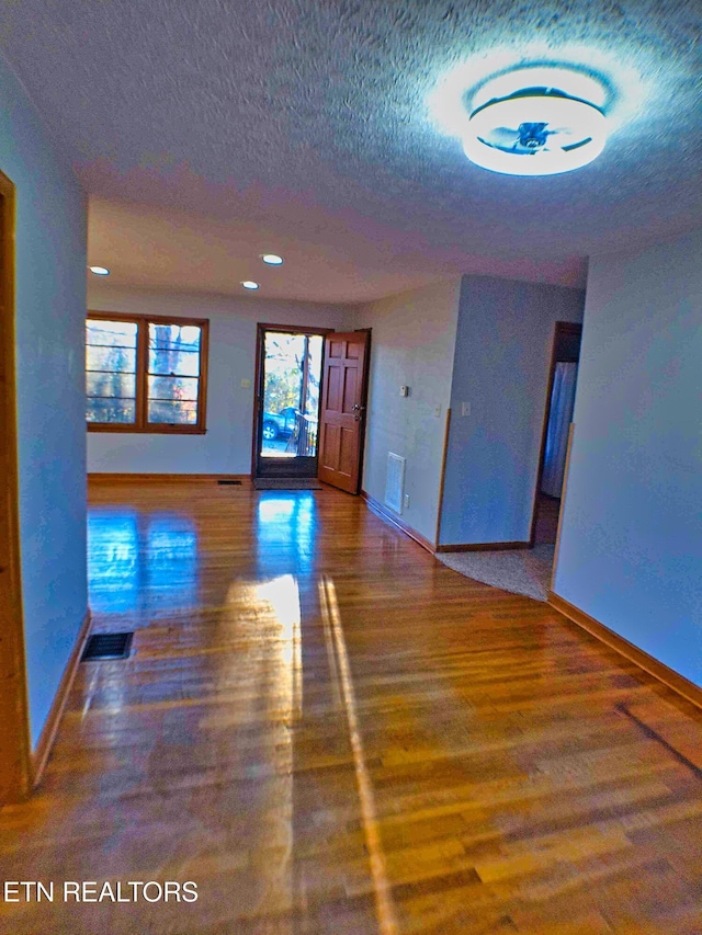 empty room with wood-type flooring and a textured ceiling