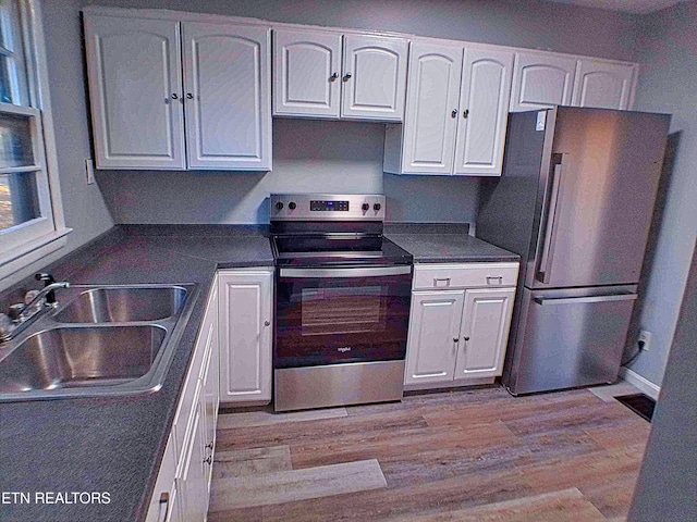 kitchen with white cabinetry, sink, light hardwood / wood-style flooring, and appliances with stainless steel finishes