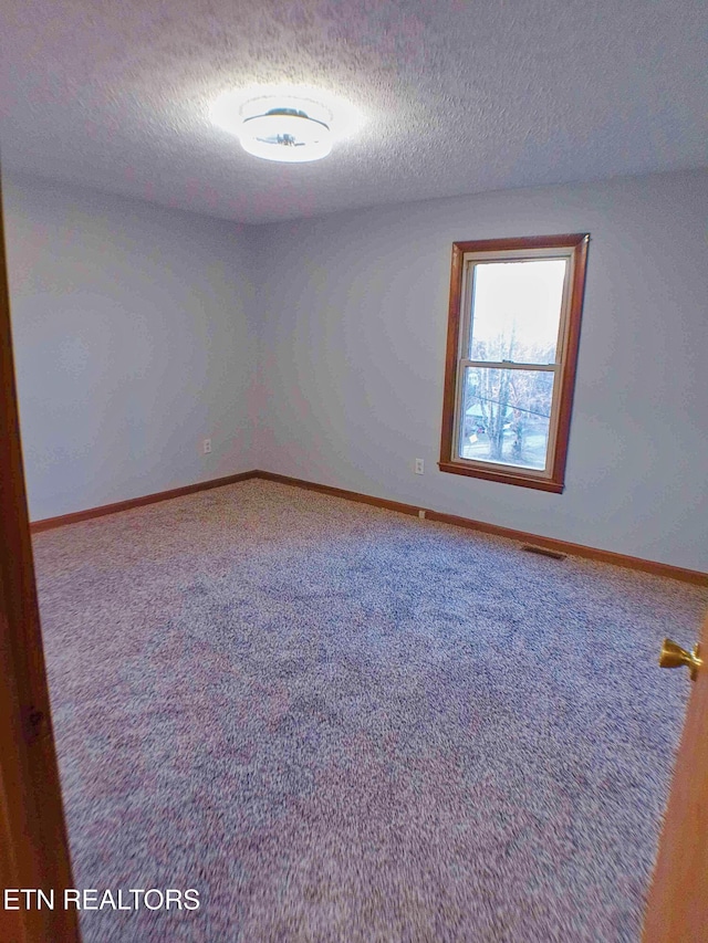 carpeted spare room with a textured ceiling