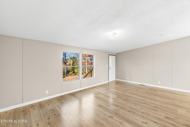 unfurnished room featuring light hardwood / wood-style floors and a textured ceiling