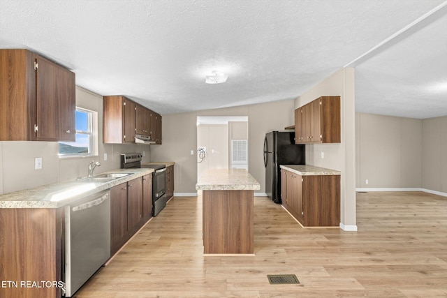 kitchen featuring a center island, sink, vaulted ceiling, light hardwood / wood-style flooring, and stainless steel appliances