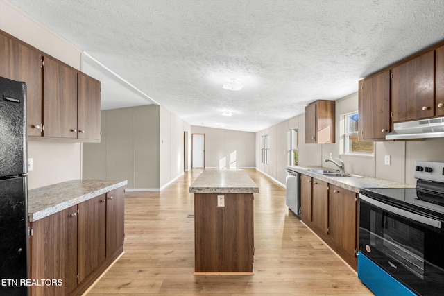 kitchen featuring appliances with stainless steel finishes, light wood-type flooring, a textured ceiling, sink, and a kitchen island