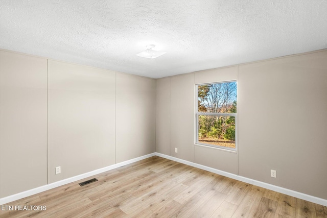 spare room with light hardwood / wood-style flooring and a textured ceiling