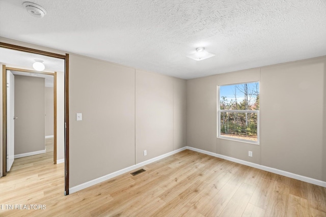 unfurnished room featuring a textured ceiling and light hardwood / wood-style flooring