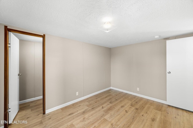 empty room with a textured ceiling and light wood-type flooring