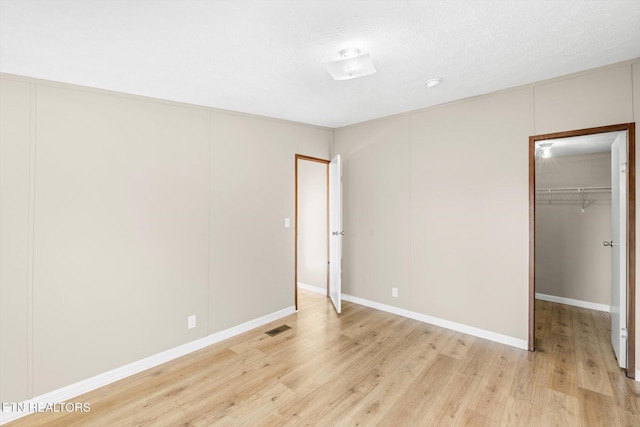 unfurnished bedroom featuring a textured ceiling, light hardwood / wood-style flooring, and a closet