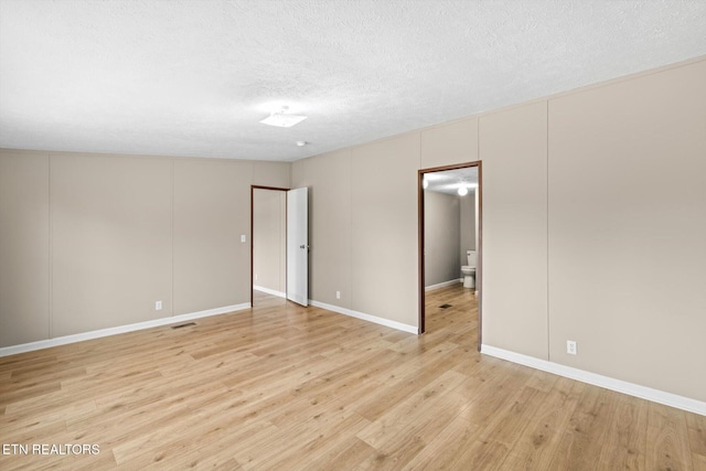 empty room with light hardwood / wood-style floors and a textured ceiling