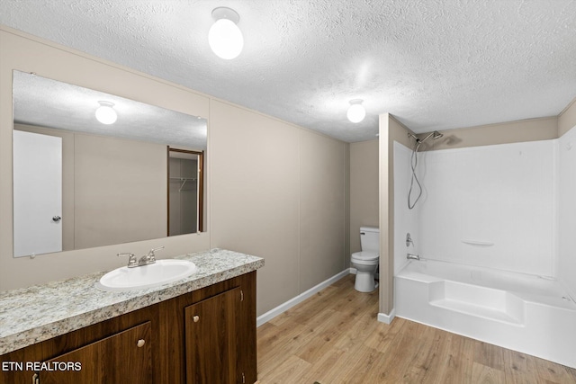 full bathroom featuring hardwood / wood-style flooring, vanity, toilet, and a textured ceiling