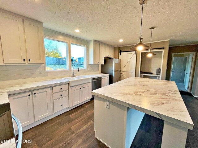 kitchen featuring stainless steel appliances, dark wood-type flooring, pendant lighting, a barn door, and white cabinetry