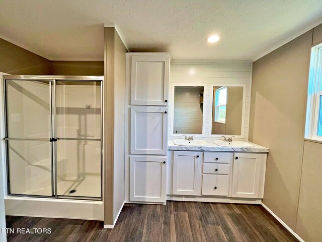 bathroom with a shower with shower door, wood-type flooring, a textured ceiling, and vanity