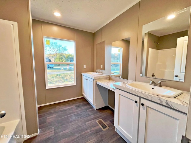 bathroom featuring wood-type flooring, vanity, a textured ceiling, and shower / washtub combination