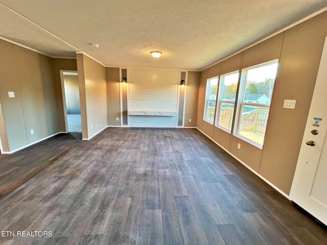 unfurnished living room with dark hardwood / wood-style floors, ornamental molding, and a textured ceiling