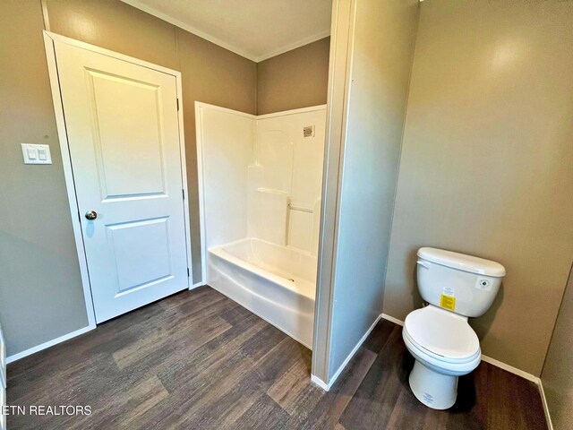 bathroom featuring hardwood / wood-style floors, toilet, and washtub / shower combination