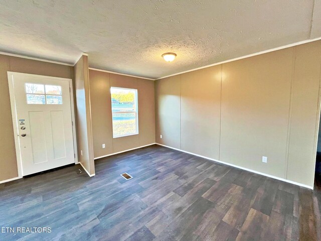 entryway featuring dark hardwood / wood-style floors, ornamental molding, and a textured ceiling