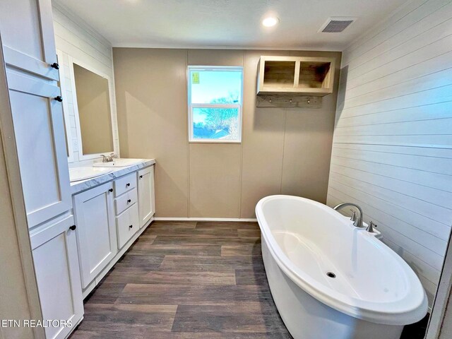 bathroom with hardwood / wood-style flooring, vanity, a tub, and wooden walls