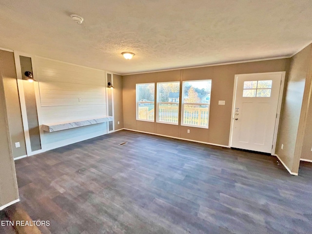 unfurnished living room with a textured ceiling and dark carpet