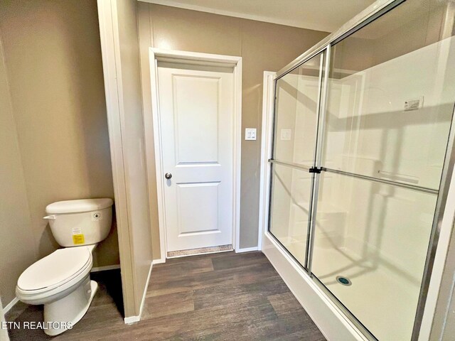 bathroom featuring hardwood / wood-style floors, toilet, and a shower with shower door