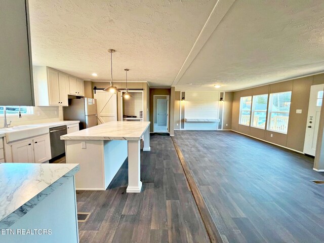 kitchen with appliances with stainless steel finishes, dark hardwood / wood-style flooring, white cabinetry, and a kitchen island