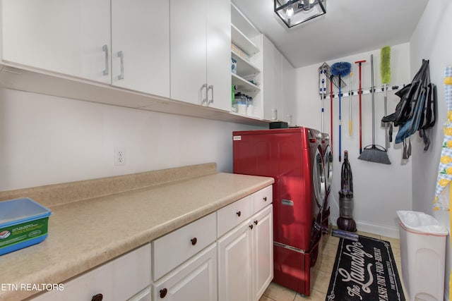 laundry room with cabinets, light tile patterned floors, and washing machine and clothes dryer