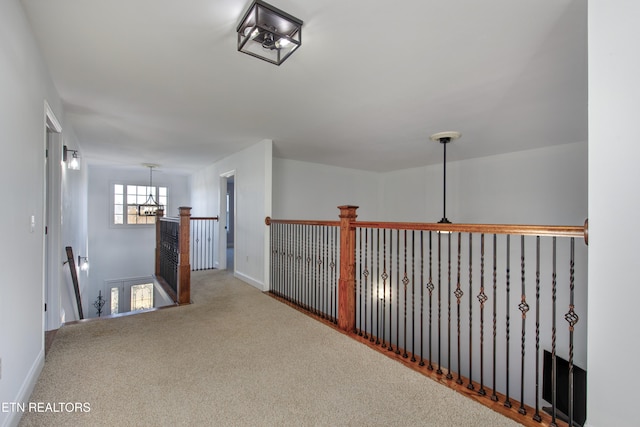 hallway featuring an inviting chandelier and carpet flooring