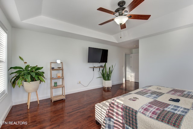 bedroom with dark hardwood / wood-style flooring, a raised ceiling, and ceiling fan