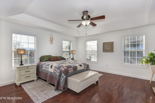 bedroom featuring a raised ceiling, dark hardwood / wood-style floors, and ceiling fan