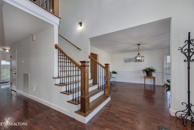 stairway with wood-type flooring and a notable chandelier